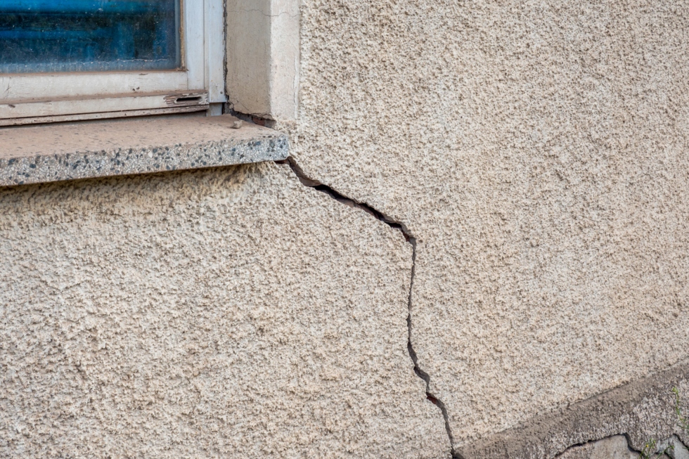 Large crack in stucco on a house wall