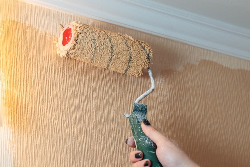 paint roller rolling over a textured wall